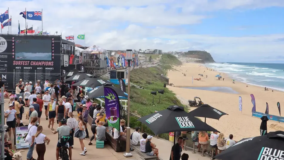 Crowds gathered at Merewether Beach for Surfest surfing competition with event signage and ocean views.