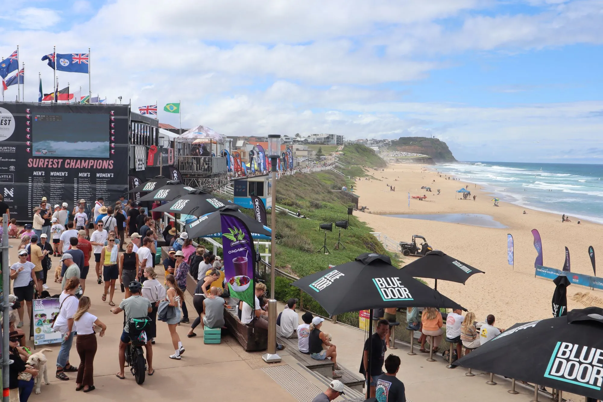 Crowds gathered at Merewether Beach for Surfest surfing competition with event signage and ocean views.