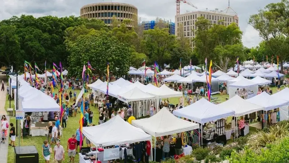 White tents and coloured streamers line an inner-city park for popular monthly markets. 