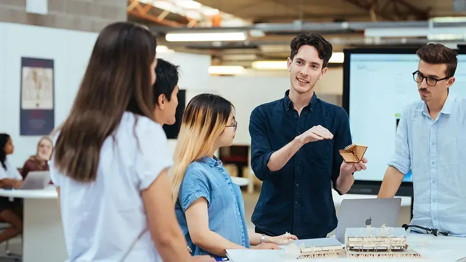 Students collaborating on architectural models and design concepts in a modern classroom at University of Newcastle.