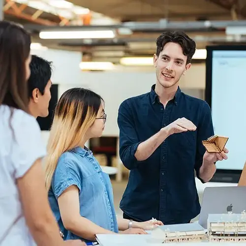 Students collaborating on architectural models and design concepts in a modern classroom at University of Newcastle.