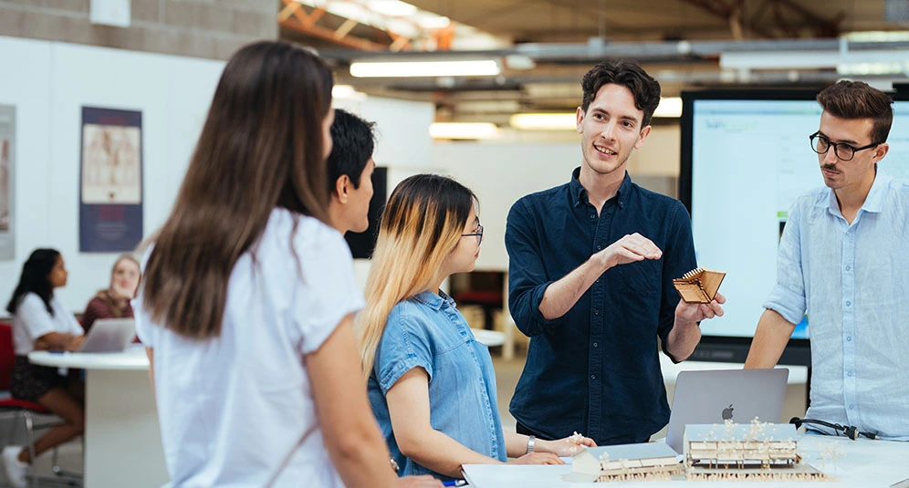 Students collaborating on architectural models and design concepts in a modern classroom at University of Newcastle.
