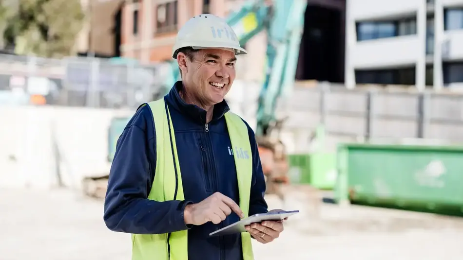 Construction worker using tablet at urban development building site for project management.