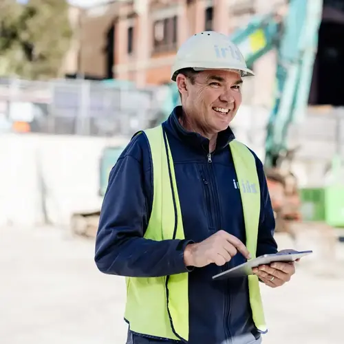 Construction worker using tablet at urban development building site for project management.