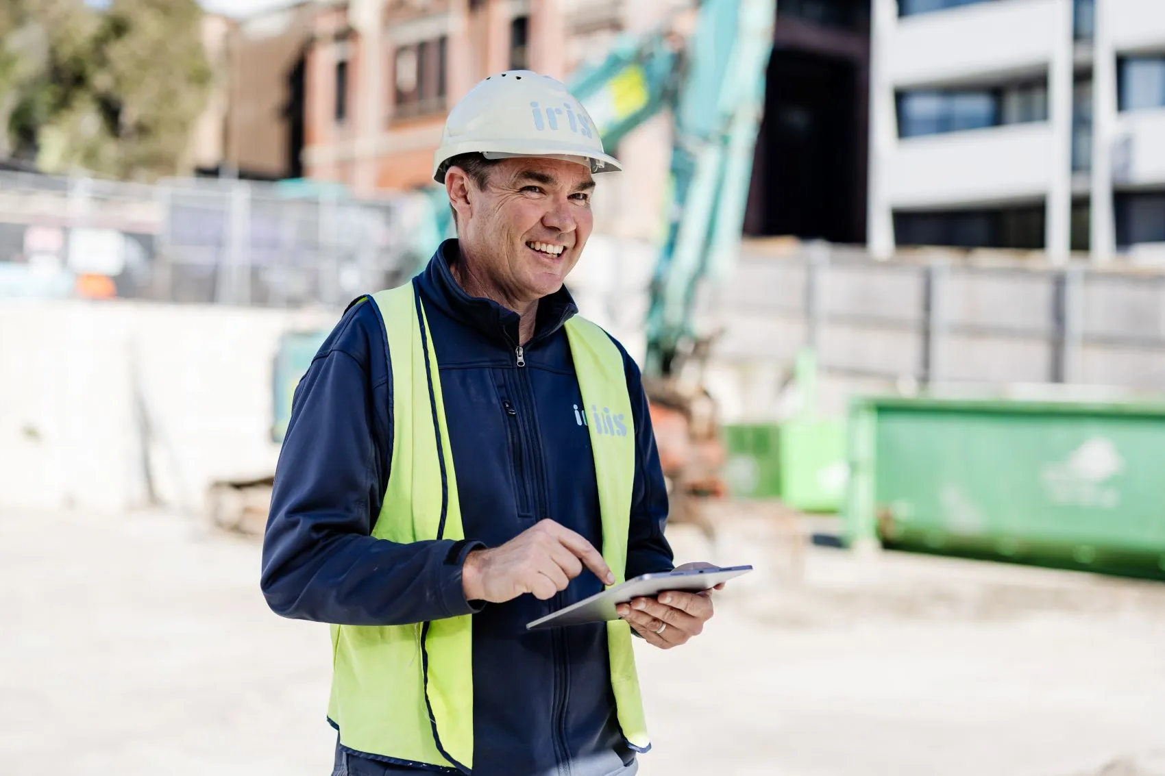 Construction worker using tablet at urban development building site for project management.