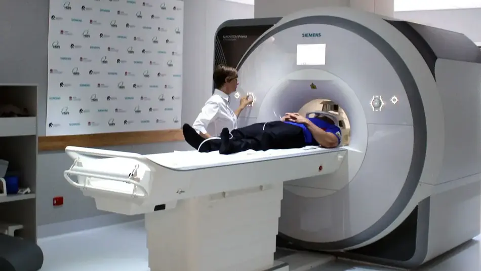 Patient undergoing MRI scan at HMRI Newcastle with technician operating Siemens MRI machine in a clinical setting.