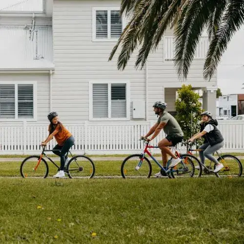 Three people ride bikes along a suburban street