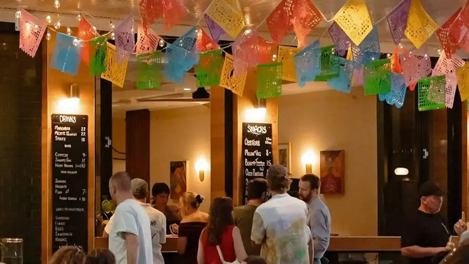 Colourful papel picado decorations at Humbug's 'Street Food Fiesta' during Newcastle Food Month with diners outside.