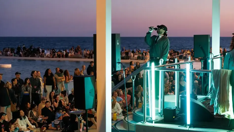 Live music performance at Newcastle Ocean Baths during sunset for New Annual festival with crowd by the water.